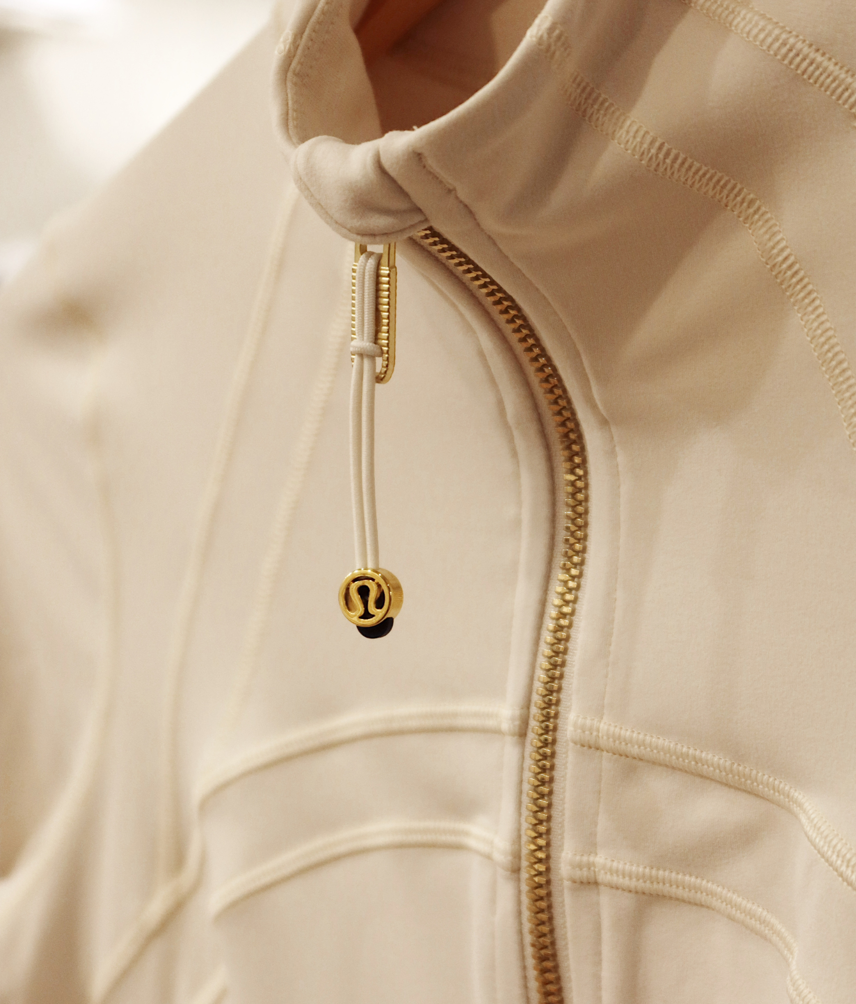 LBI National Golf & Resort cream-colored athletic jacket with gold zipper and branded drawstring detail