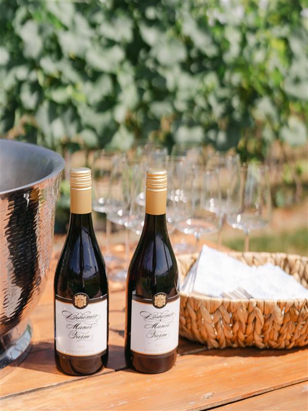 Two bottles of wine on a wood table outside