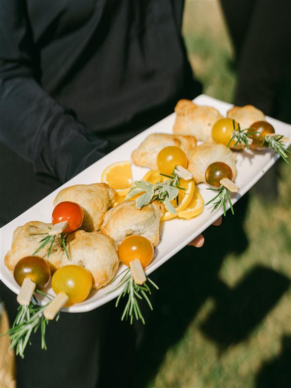An hors d'oeuvres tray held by an attendant wearing all black clothing.
